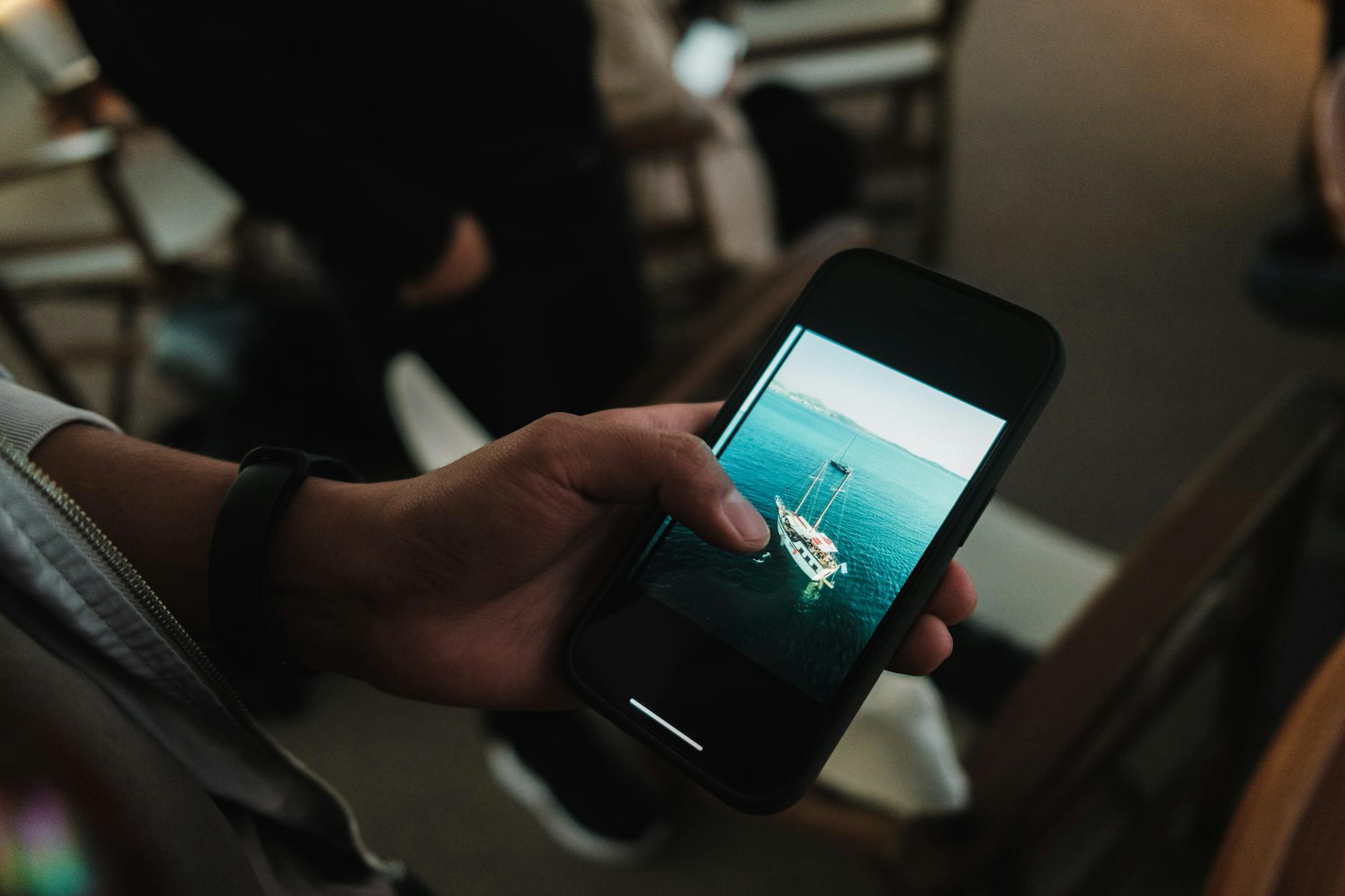 a person holding a cell phone with a photo of a boat